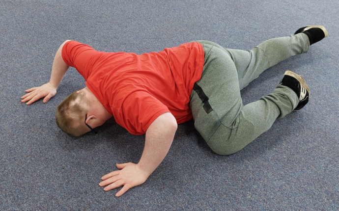 An image of a man in a red top leaning on the floor in a contemporary dance move. 