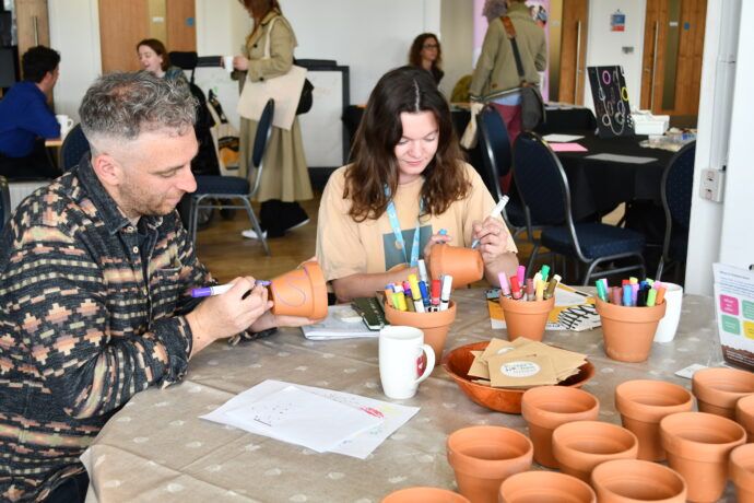 This is a picture of two people drawing on some flower pots. 