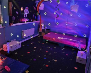 A photo of the new sensory room, which shows moving lighting, a space scene, colourful decorations hanging from the ceiling and the water bed.