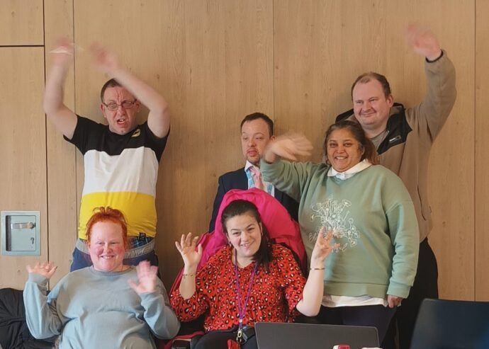 The People's Forum smiling and waving at the camera. They are in a meeting room. 