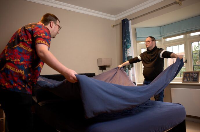 An image of two men working together to make a bed.